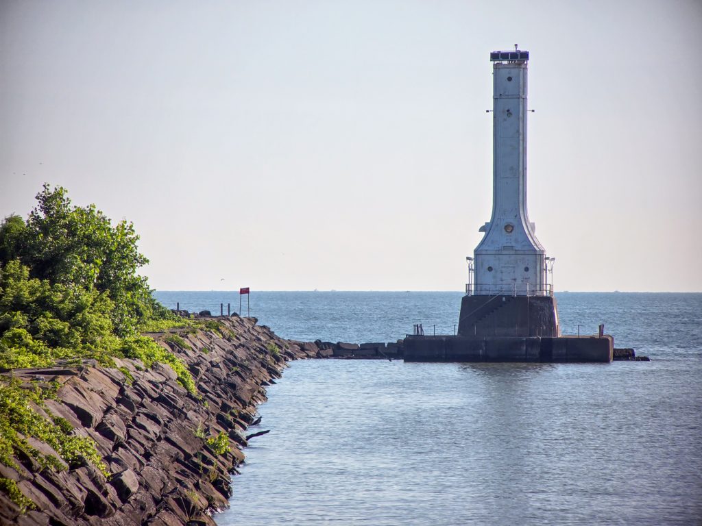 Huron Lighthouse at the end of a long pier with calm morning waters in Huron, Ohio