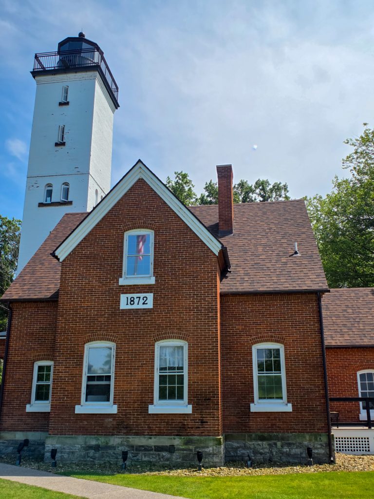 Presque Isle Lighthouse surrounded by beach grass and Lake Erie shoreline
